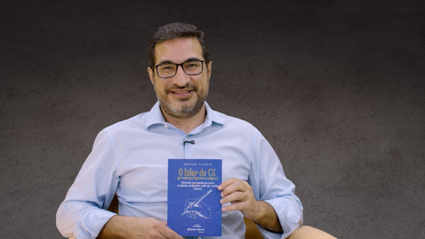Rodrigo Tavares segura o livro O líder de CX durante a gravação de sua entrevista ao Cobogós